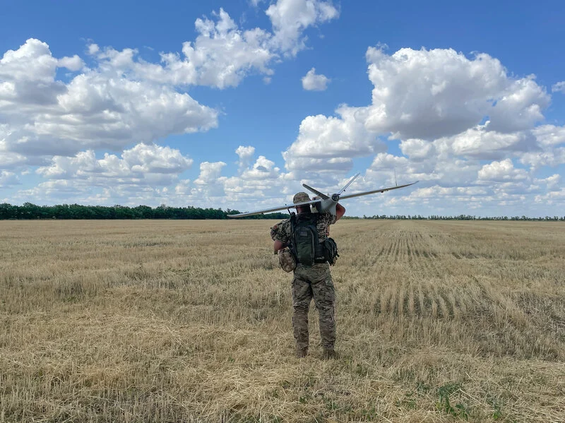 Grayscale photograph of an open field with a small drone in the distance.
